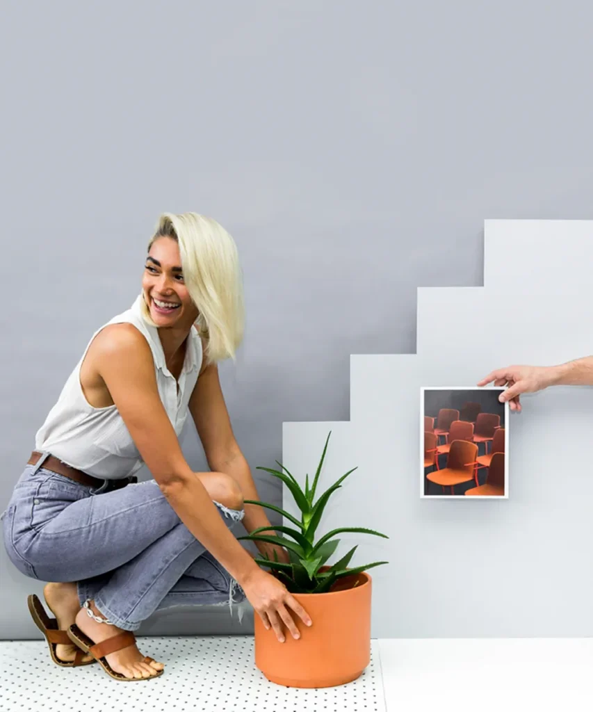 Certificate IV in Design (Styling) student styling a potted plant and artwork against a grey wall